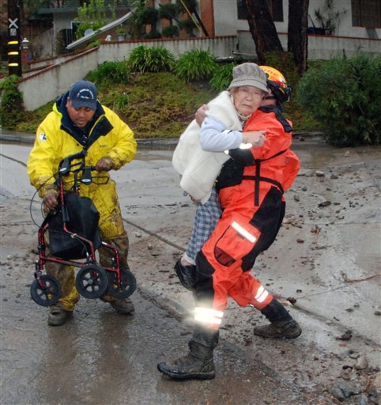 A Los Angeles County Fire Department Urban Search and Rescue (USAR) member, carries a 91-year-old woman from her flood-damaged home on Ocean View Boulevard Saturday, Feb. 6, 2010 in La Canada Flintridge, Calif. (AP Photo/Mike Meadows)